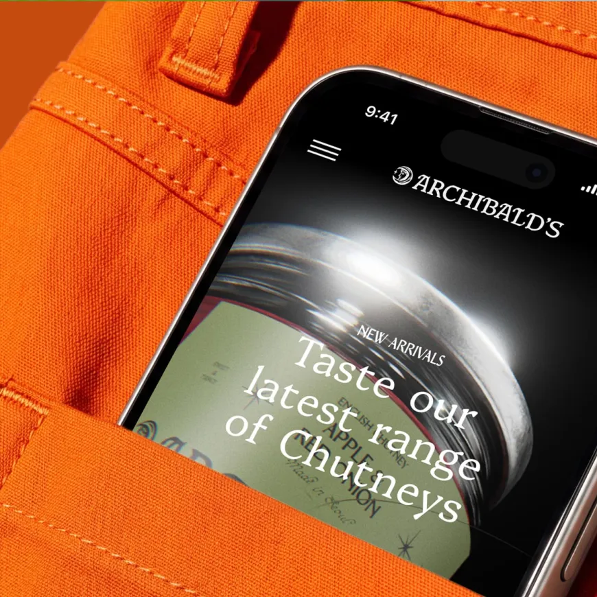Mobile phone peeping out of a back pocket of bright orange jeans