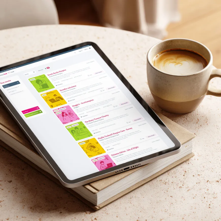 Tablet mockup of Brain Tumour Hub resources search page, laid on a coffee table and book.