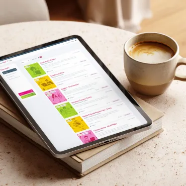 Tablet mockup of Brain Tumour Hub resources search page, laid on a coffee table and book.
