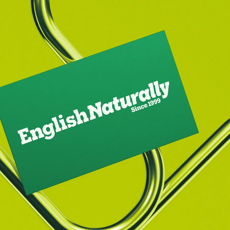 English Naturally business card displayed on a vivid green background with curved metallic elements