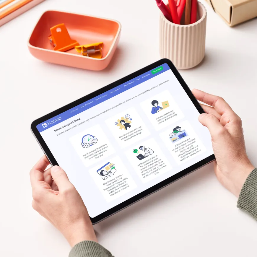 Person holding a tablet device with the Harrap website displaying