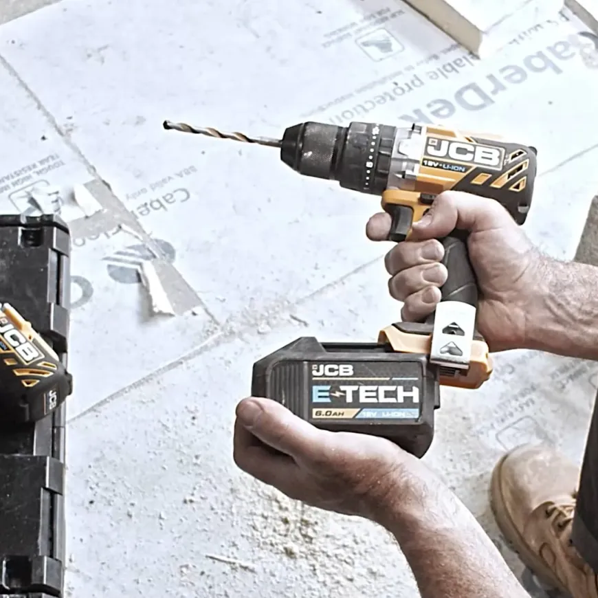 a man in orange hi vis changes the batter on a jcb drill
