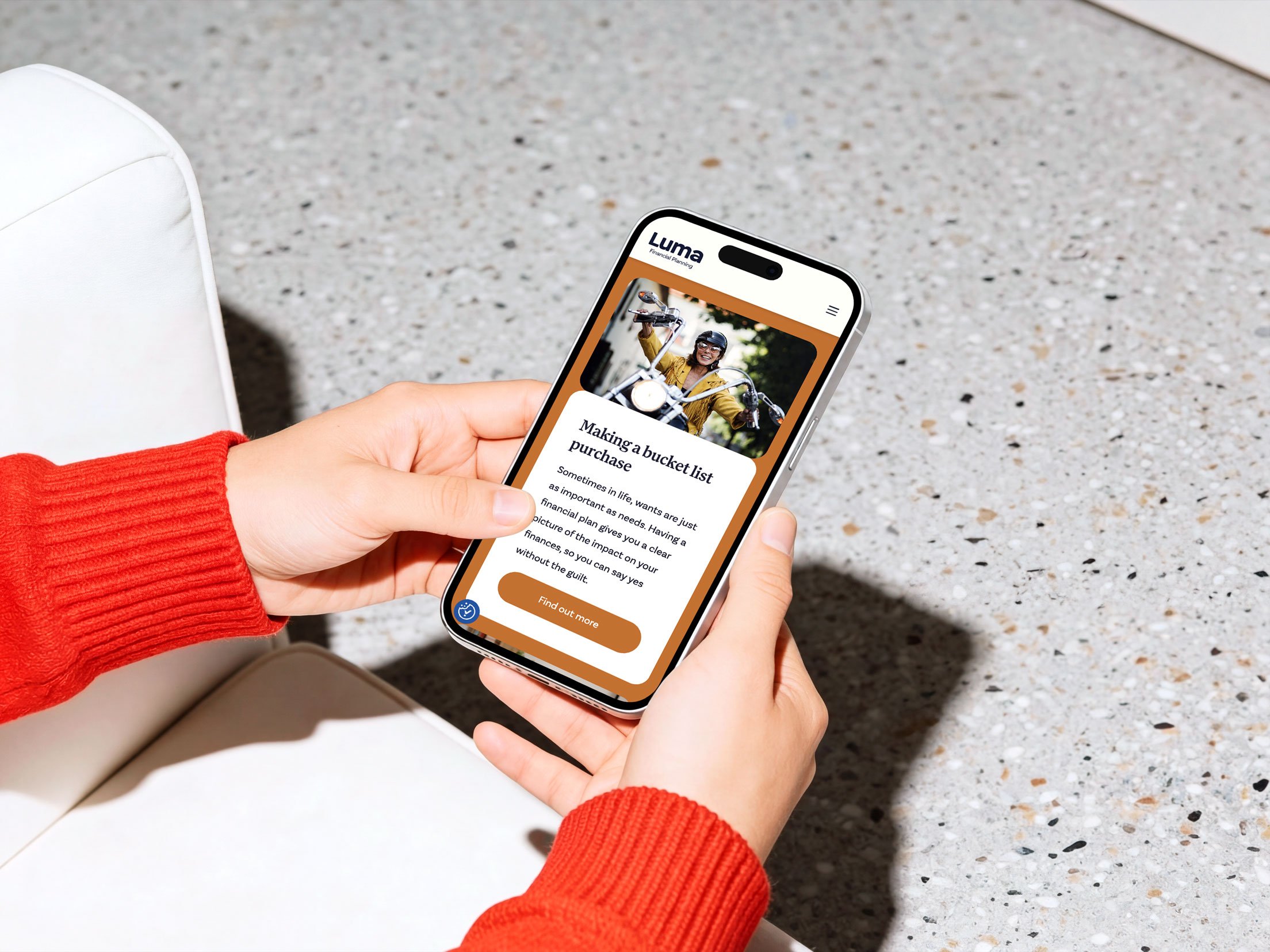 Person holding a smartphone displaying the Luma Financial Planning website with an article about making a bucket list purchase