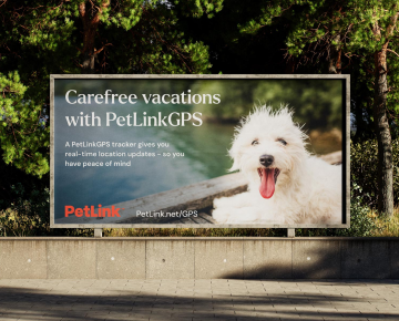 Fluffy white terrier sized dog sticking its tongue out in an image on a PetLinkGPS advert billboard.