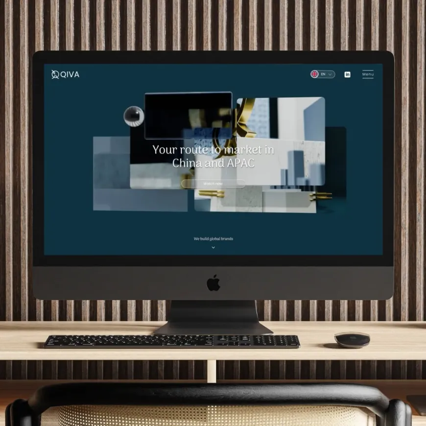 a mac computer screen on a wooden desk displaying the qiva global website