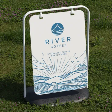 a white a board on green grass featuring river coffee branding