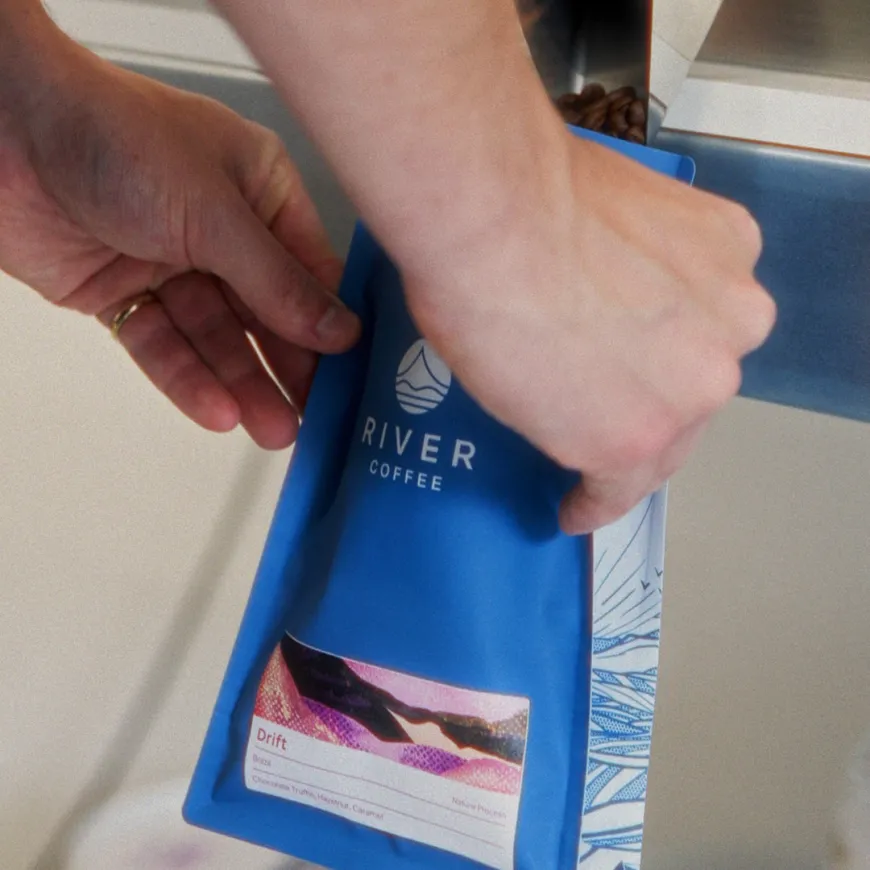 a blue coffee bag being filled with coffee beans