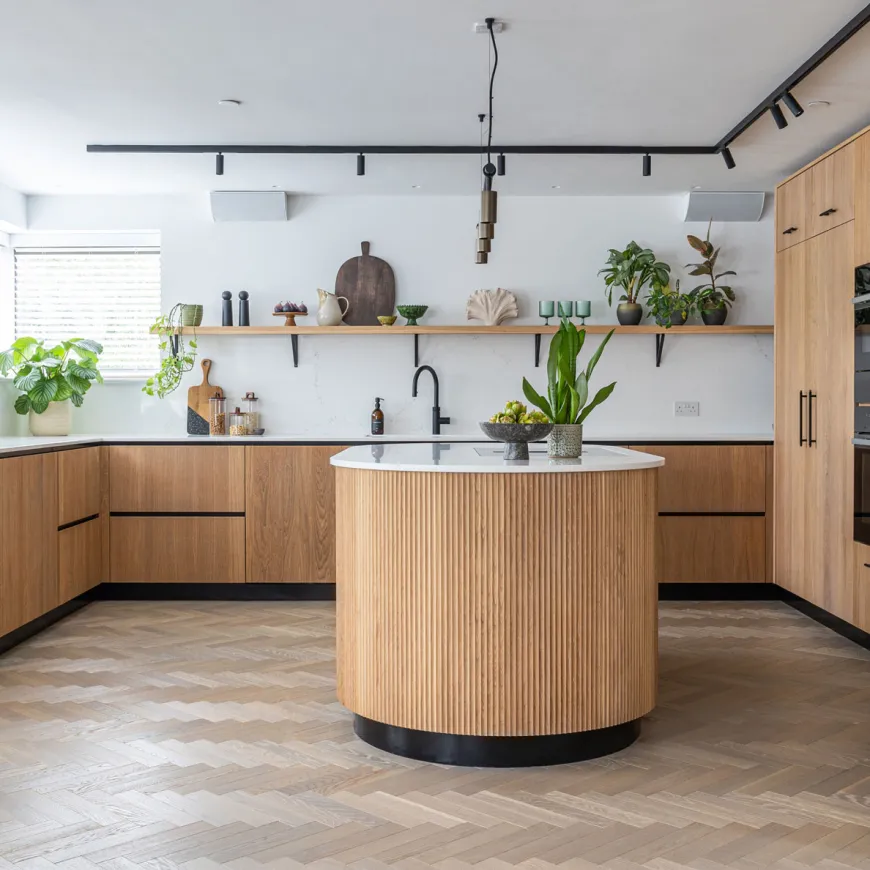 Contemporary kitchen with wood cabinetry and a curved fluted island