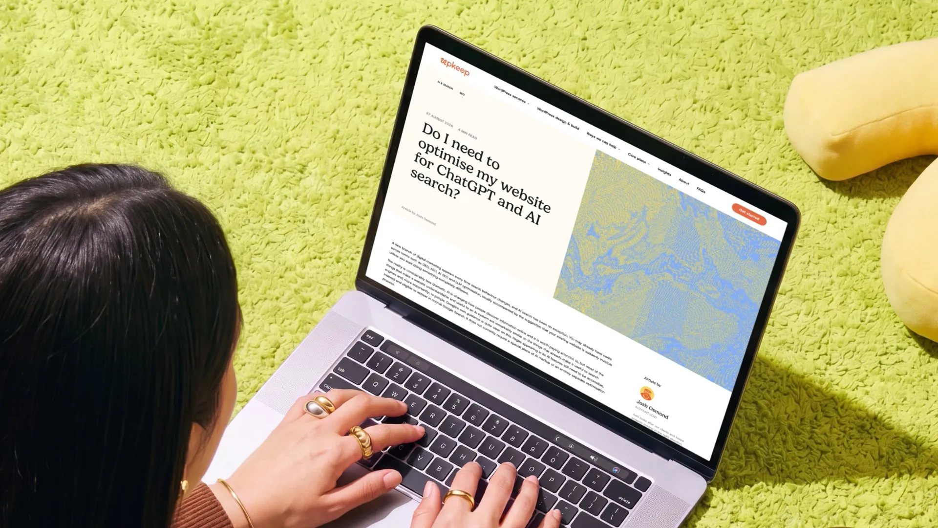 Mockup of a laptop open on the Upkeep insights page, being used by a woman with dark hair on a bright lime green carpet.