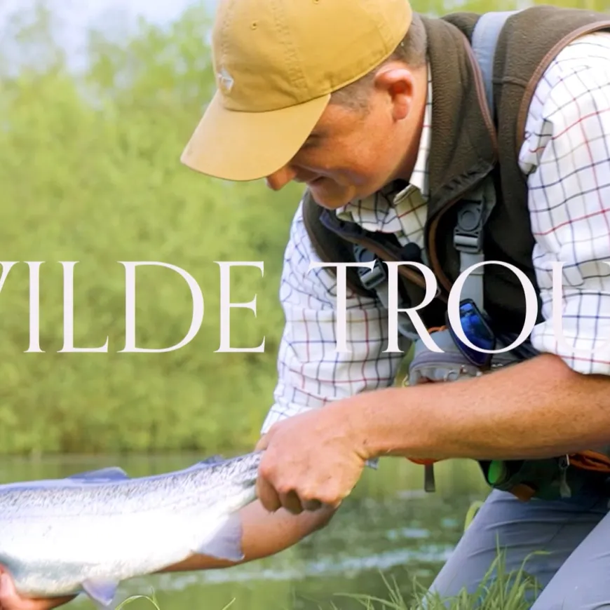 Photo of man and child fishing, man holding large trout. With Wilde Trout written over top of image.