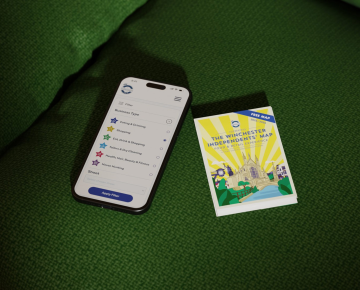 Mobile phone with search filter mockup and Winchester map on a green sofa.